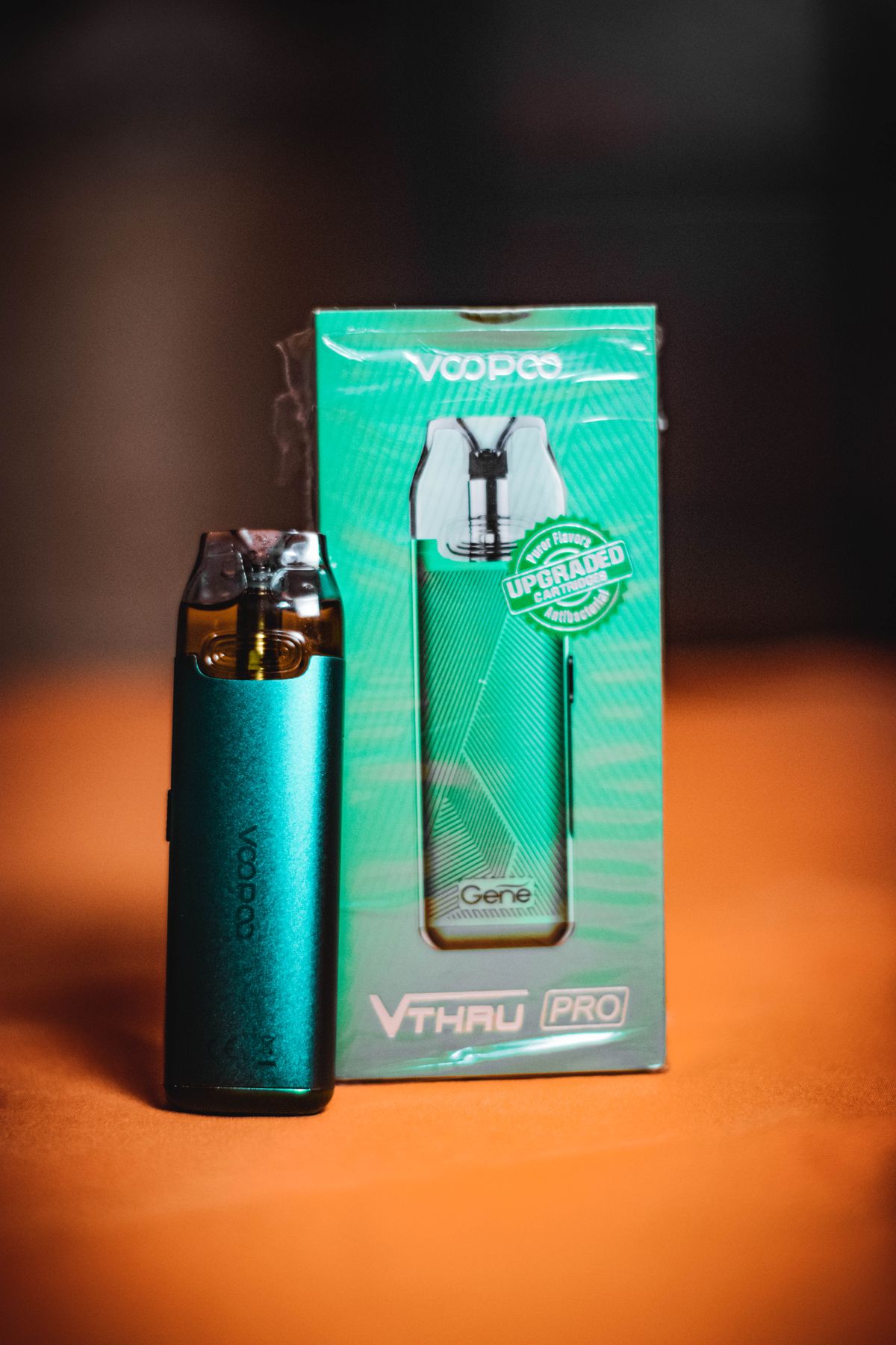 Türkisfarbenes Pod-Vape-Gerät mit Verpackung auf orangefarbenem Untergrund