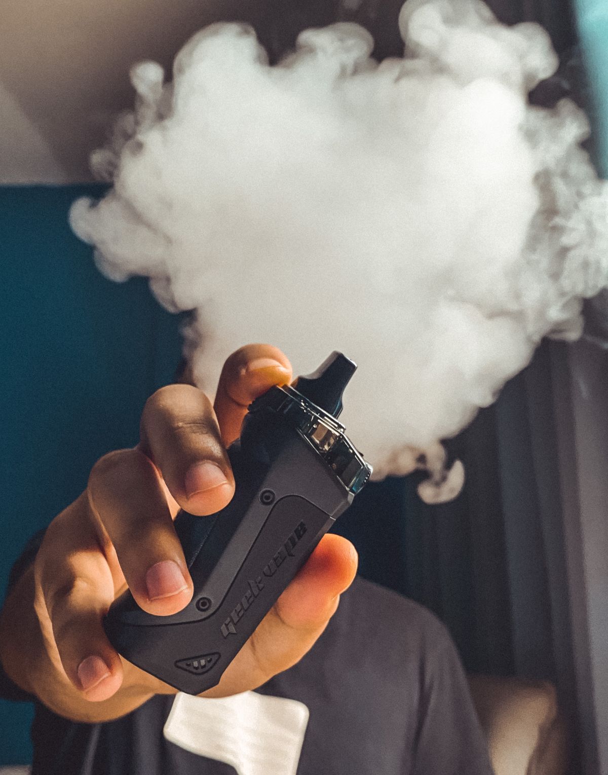 Hand hält ein Vape-Gerät mit sichtbarer Dampfwolke