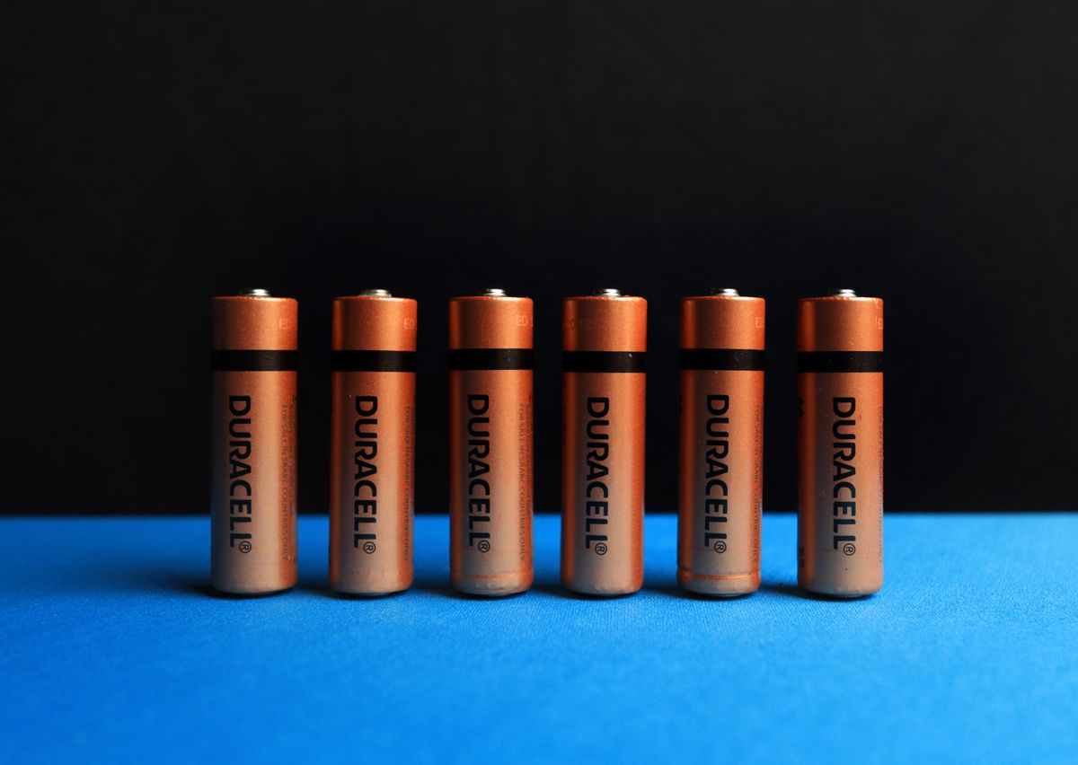 Aufgereihte AA-Batterien vor schwarz-blauem Hintergrund