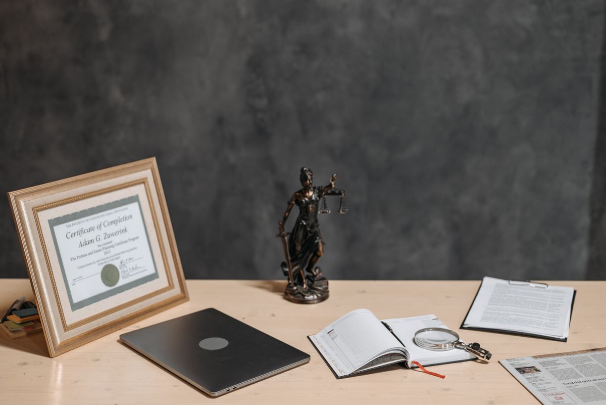 Symbolbild: Schreibtisch mit Dokumenten, Statue und Laptop