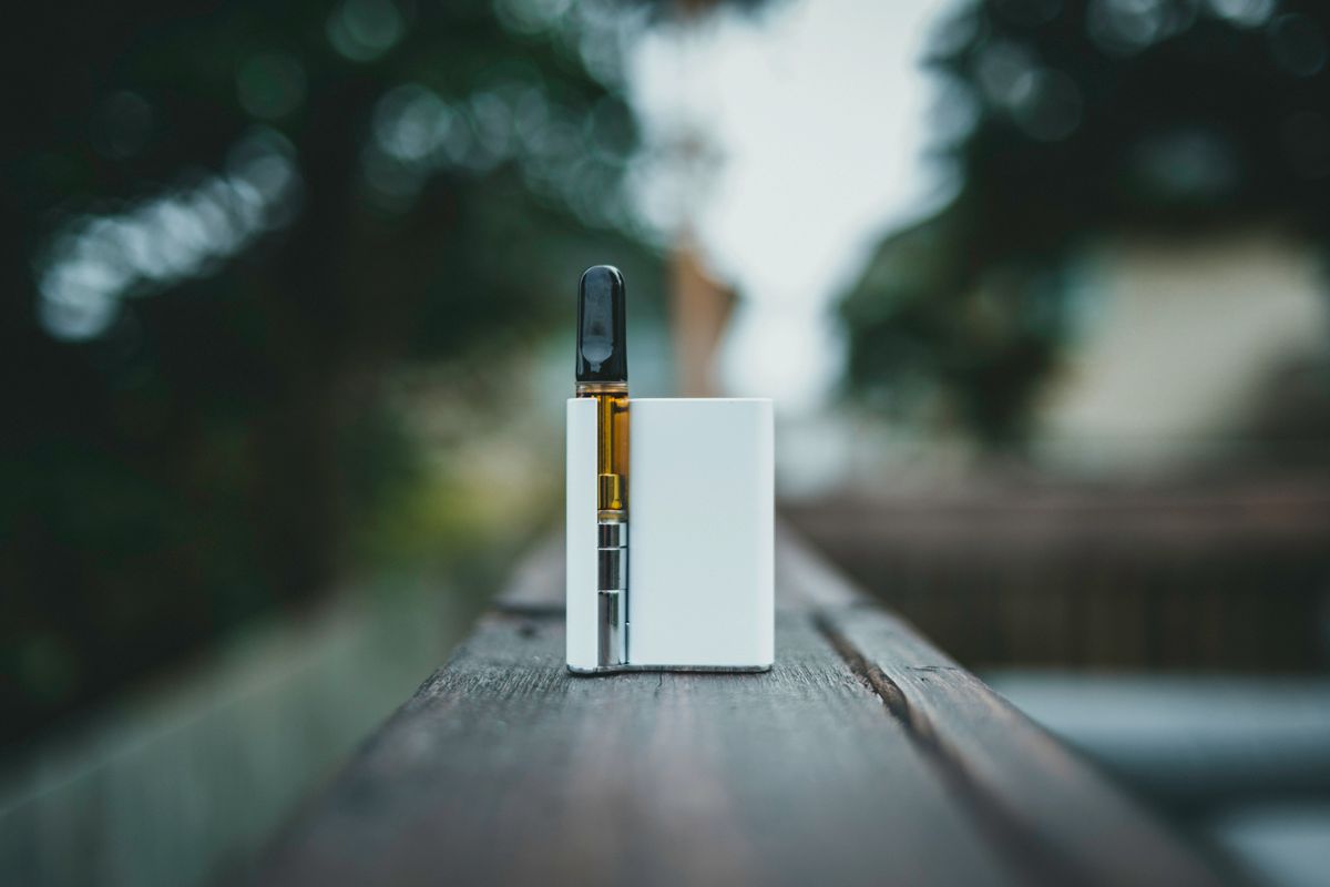 Schlankes Vape-Gerät auf einer Holzoberfläche im Freien